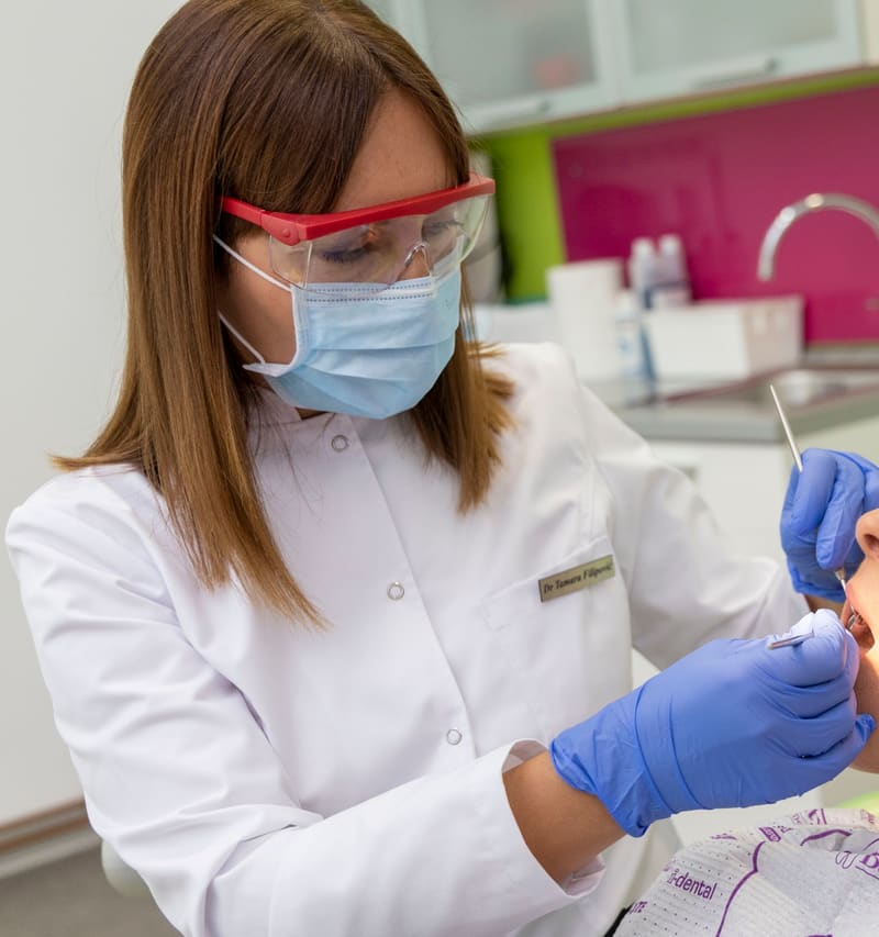 Dr Tamara Filipović, u belom mantilu i sa zaštitnim naočarima, pregleda pacijentkinju u stolici.